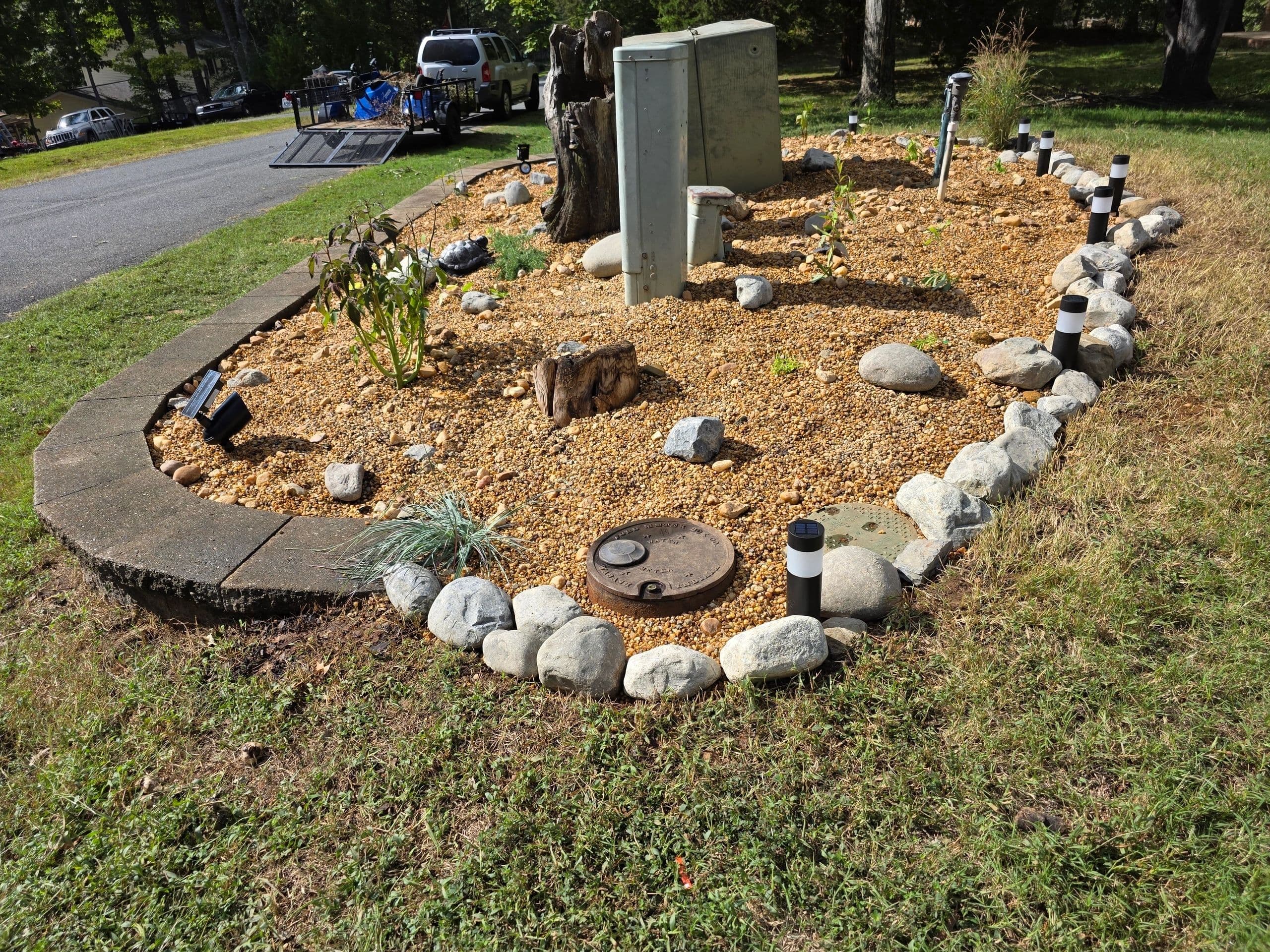 Circular rock and mulch bed with landscape lighting stakes